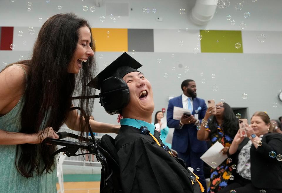 George Benschoter and his teacher Rachel Gabriel exit under a shower of bubbles at his graduation ceremony Wednesday at Rosedale School. Twelve students graduated from the Austin school that serves people with significant disabilities.