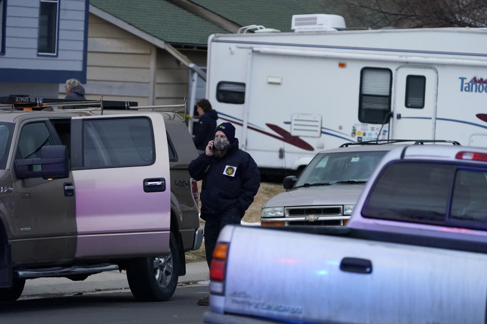 A National Transportation Safety Board investigator talks on his mobile device in the street near a home peppered by parts from a plane as it was making an emergency landing at nearby Denver International Airport Saturday, Feb. 20, 2021, in Broomfield, Colo. (AP Photo/David Zalubowski)