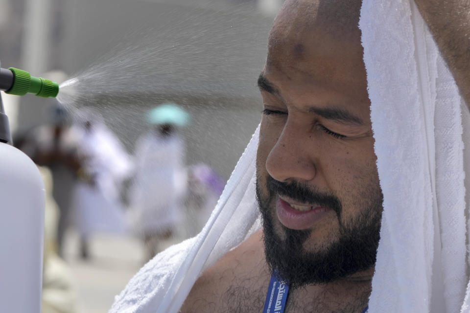 A pilgrim receives cold water spray after he casts stones at a pillar in the symbolic stoning of the devil, the last rite of the annual Hajj pilgrimage, in Mina near the holly city of Mecca, Saudi Arabia, Thursday, June 29, 2023. (AP Photo/Amr Nabil)