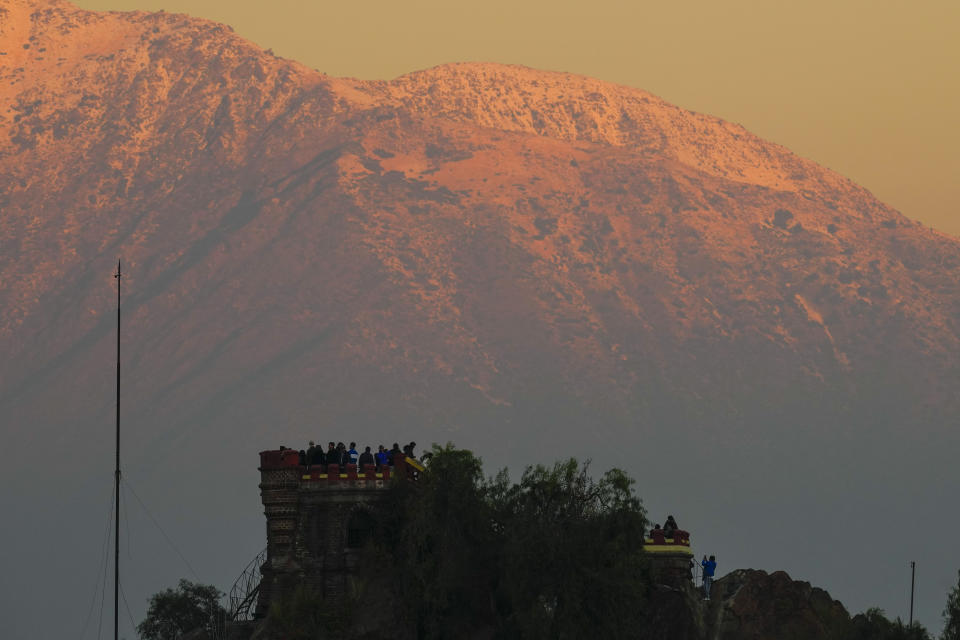The afternoon sun illuminates the Andes blanketed by snow while visitors take pictures form Santa Lucia hill, in Santiago, Chile, Wednesday, May 8, 2024. (AP Photo/Esteban Felix)