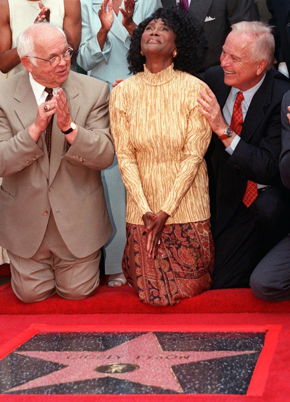 FILE - Academy Award-nominated actress Cicely Tyson reacts to the unveiling of her star on the Hollywood Walk of Fame in the Hollywood section of Los Angeles, Thursday, Aug. 21, 1997. Honorary Mayor of Hollywood and chairman of the Walk of Fame committee Johnny Grant, left, and Los Angeles Mayor Richard Riordan joined Tyson for the unveiling. Tyson, the pioneering Black actress who gained an Oscar nomination for her role as the sharecropper's wife in "Sounder," a Tony Award in 2013 at age 88 and touched TV viewers' hearts in "The Autobiography of Miss Jane Pittman," has died. She was 96. Tyson's death was announced by her family, via her manager Larry Thompson, who did not immediately provide additional details. (AP Photo/Damian Dovarganes, File)