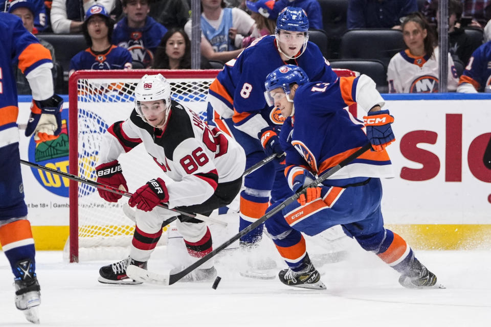 New Jersey Devils' Jack Hughes (86) fights for control of the puck with New York Islanders' Mathew Barzal (13) and Noah Dobson (8) during the overtime period of an NHL hockey game Friday, Oct. 20, 2023, in Elmont, N.Y. (AP Photo/Frank Franklin II)