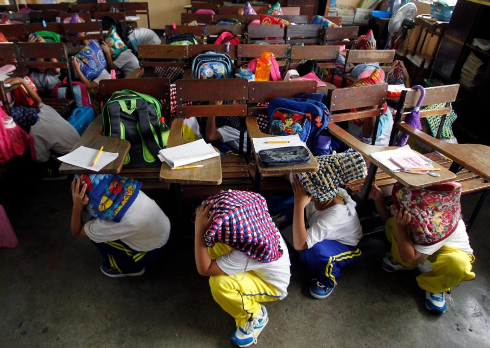 FILE PHOTO: Filipino elementary pupils use protective head gears as they hide under their desks during a simultaneous nationwide earthquake drill in Pasig, Metro Manila June 29, 2012. Tens of thousands of students all over the country took part in a quarterly earthquake drill on Friday to react properly during high intensity earthquakes, disaster prevention officials said. (Source: REUTERS/Erik De Castro)