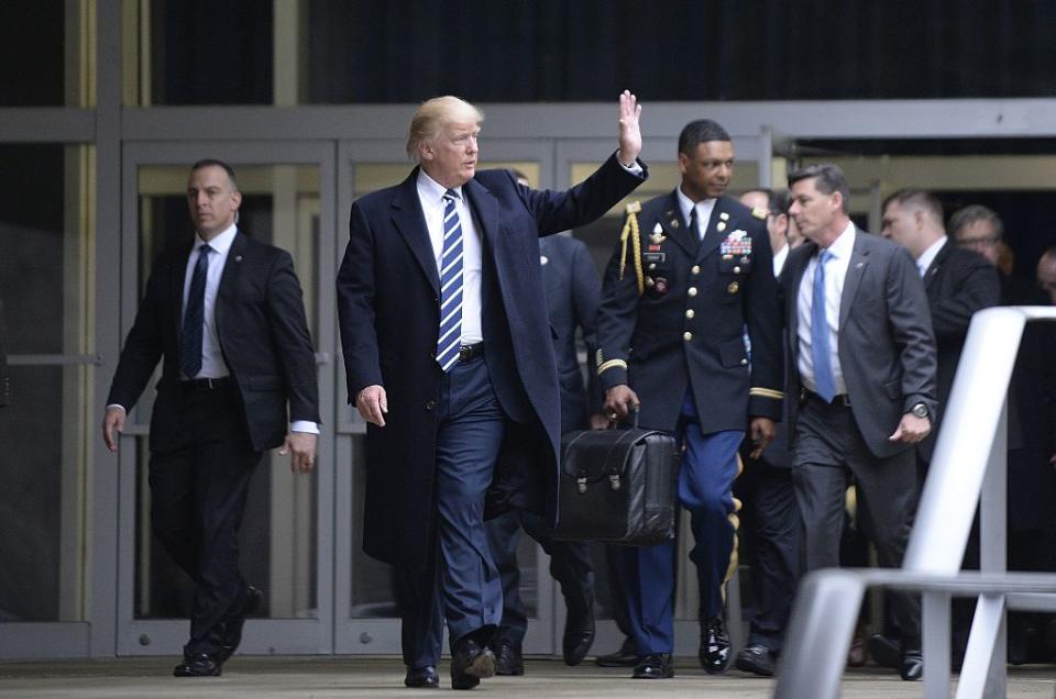 US President Donald Trump leaves the CIA headquarters after speaking to 300 people on January 21, 2017 in Langley, Virginia . Trump spoke with about 300 people in his first official visit with a government agency. In the background a military aid carries the 'football', with launch codes for nuclear weapons. <span class="copyright">Olivier Doulier-Getty Images</span>