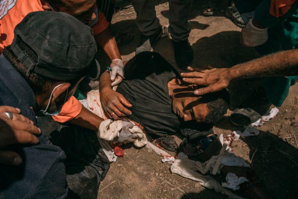 Paramedics assist a man who was injured in the chest and arms by Israeli troops along the Gaza border.