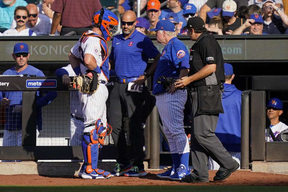 New York Mets catcher James McCann, left, speaks with manager Buck Showalter, center right, before he exits the game in the sixth inning of a baseball game against the Miami Marlins, Saturday, July 9, 2022, in New York. (AP Photo/John Minchillo)