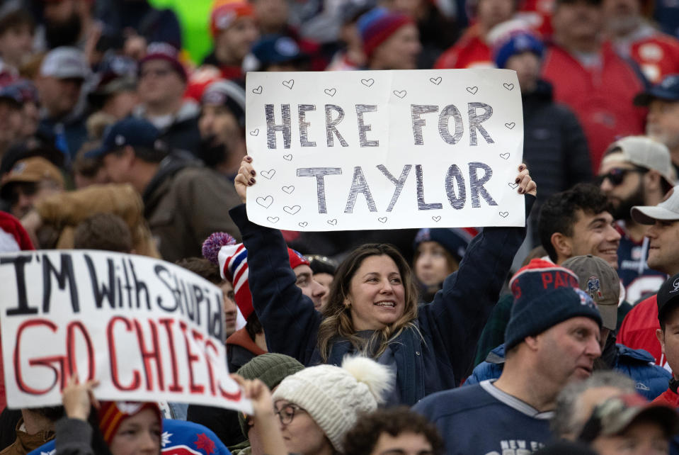 Fans holding Taylor Swift signs in the crowd