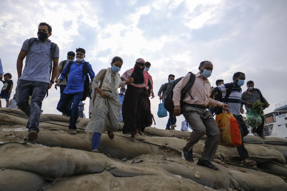 Thousands of people leaving for their native places to celebrate Eid-al-Fitr rush to the Mawa ferry terminal ignoring risks of coronavirus infection in Munshiganj, Bangladesh, Thursday, May 13, 2021. (AP Photo/Mahmud Hossain Opu)