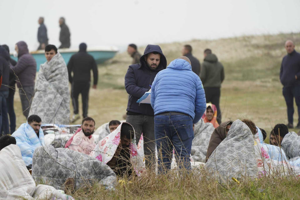 Rescued migrants sit covered in blankets at a beach near Cutro, southern Italy, Sunday, Feb. 26, 2023. Nearly 70 people died in last week's shipwreck on Italy's Calabrian coast. The tragedy highlighted a lesser-known migration route from Turkey to Italy for which smugglers charge around 8,000 euros per person. (Antonino Durso/LaPresse via AP, File)