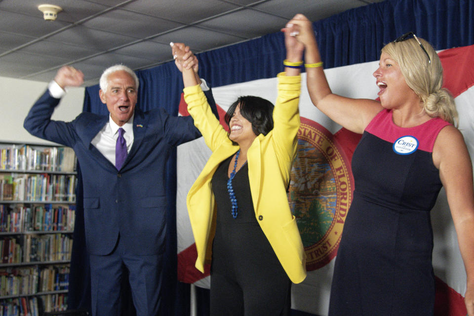 U.S. Rep. Charlie Crist,left, and his fiancé Chelsea Grimes, right, celebrate as he announces his running mate Karla Hernández-Mats, center, at Hialeah Middle School in Hialeah, Fla., Saturday Aug. 27, 2022 as he challenges Republican Gov. Ron DeSantis in November (AP Photo/Gaston De Cardenas)