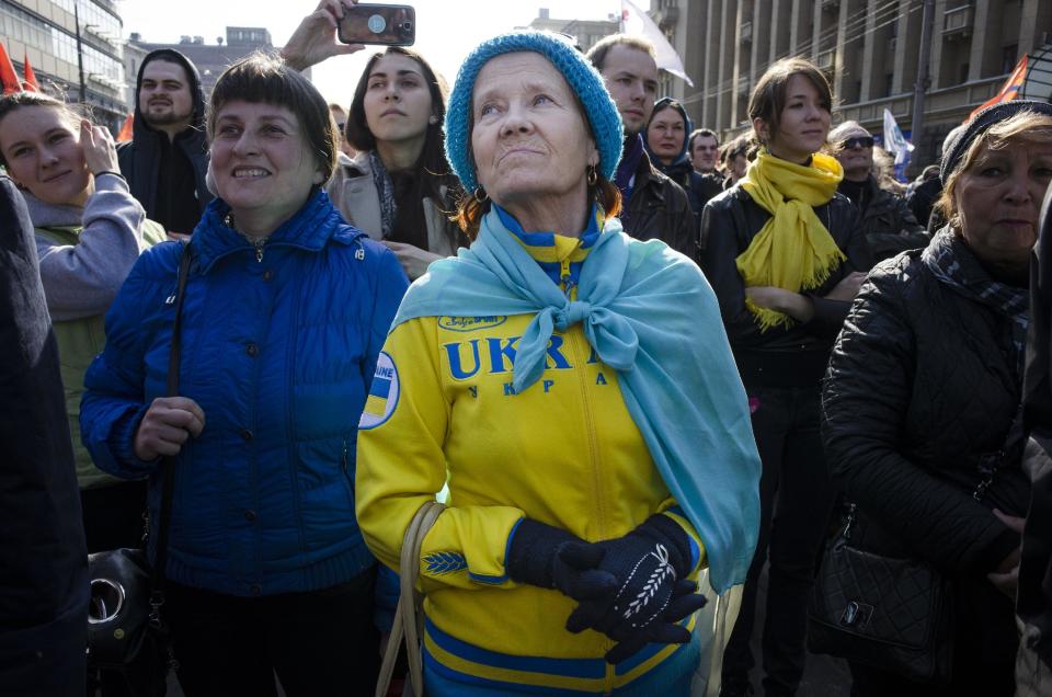 A woman wearing clothes in the color of the Ukrainian flag listens to a speaker during a rally against pro-Putin media in Moscow, Russia, Sunday, April 13, 2014. More than 10,000 people have turned out in Moscow for an anti-Kremlin rally to denounce Russian state television’s news coverage, particularly of the crisis in neighboring Ukraine. (AP Photo/Alexander Zemlianichenko)