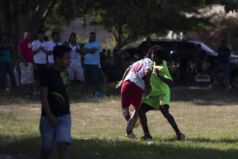 Players from a taxi drivers' team, center left, and a gang members' team vie for the soccer ball during a game in the Rivera Hernandez neighborhood of San Pedro Sula, Honduras, on Dec. 1, 2019. With the help of neighbors, an evangelical pastor organized a zone of tolerance in the field where 14 people were killed in 2010, during an inter-gang battle for control of the area. (AP Photo/Moises Castillo)