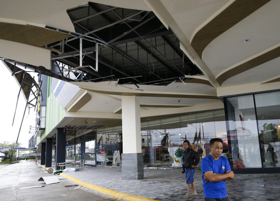 Residents stand beside a damaged portion of a mall due to strong winds from Typhoon Mangkhut as it barreled across Tuguegarao city in Cagayan province, northeastern Philippines on Saturday, Sept. 15, 2018. The typhoon slammed into the Philippines northeastern coast early Saturday, it's ferocious winds and blinding rain ripping off tin roof sheets and knocking out power, and plowed through the agricultural region at the start of the onslaught. (AP Photo/Aaron Favila)