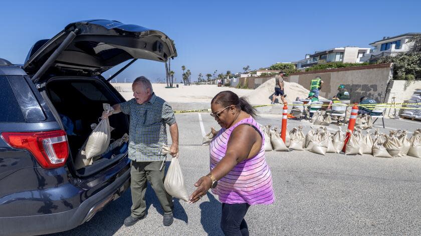 Seal Beach, CA - August 18: John Straub, left, a volunteer with West Orange County Community Emergency Response Team (CERT) loads sandbags for Cynthia Abernathy, of Lakewood, who plans to fortify her home ahead of anticipated high surf, strong winds and flooding from the approaching Hurricane Hilary in Seal Beach Friday, Aug. 18, 2023. As Hurricane Hilary continues its march toward Southern California, officials have issued an unprecedented tropical storm watch for the region. The watch is in effect for much of southwestern California, from the San Diego deserts to the San Bernardino County mountains and onto Catalina Island, something the National Hurricane Center said is a first for this area. A tropical storm watch indicates that tropical storm conditions are possible - meaning more than 39 mph sustained winds - within 48 hours, according to the hurricane center. (Allen J. Schaben / Los Angeles Times)