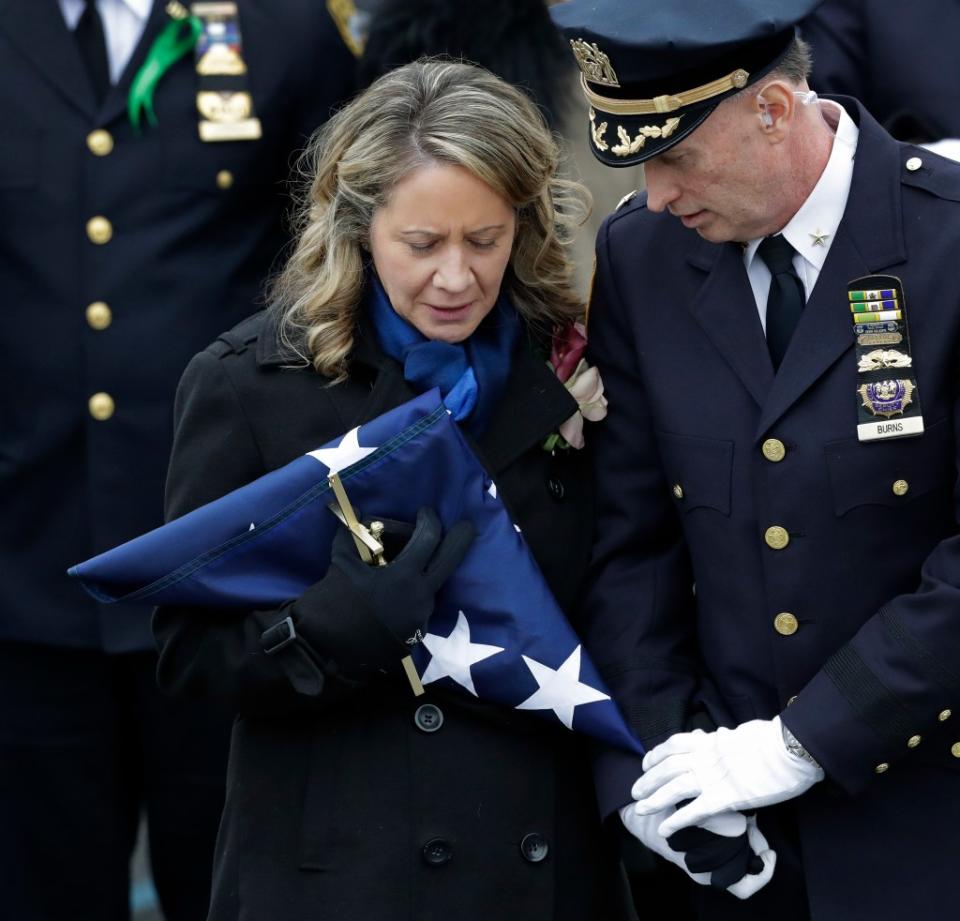 Leanne Simonsen, the widow of Det. Brian Simonsen, holds the flag that draped his casket following his funeral at the Church of St. Rosalie in Hampton Bays, N.Y., Wednesday, Feb. 20, 2019. AP