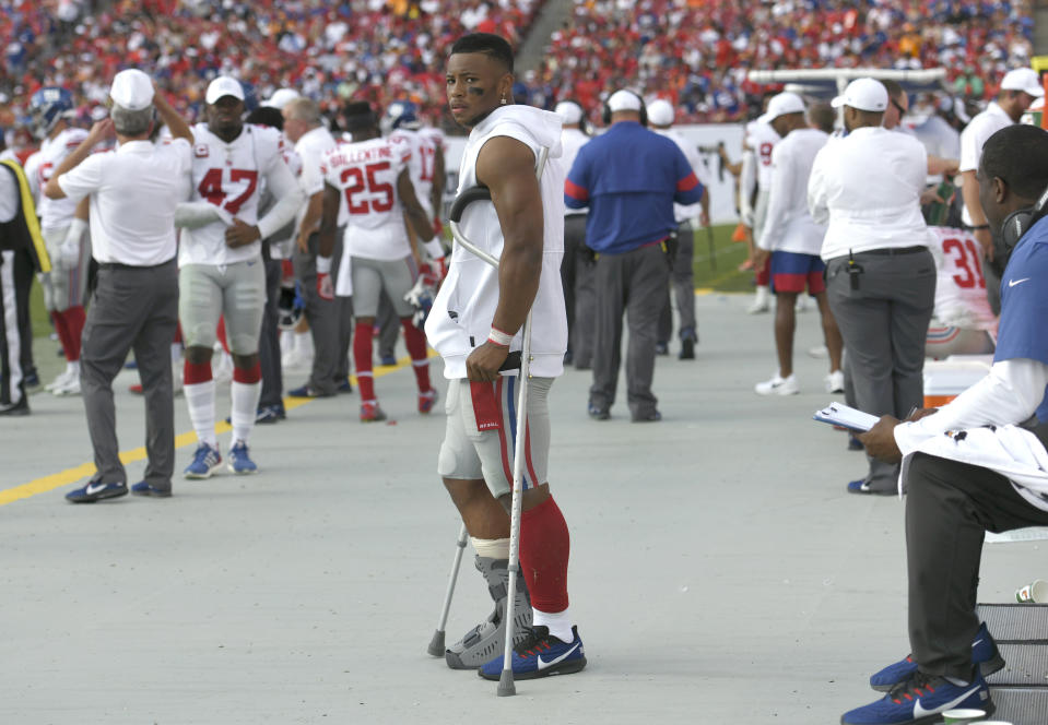 New York Giants running back Saquon Barkley stands on crutches in the bench area. (AP)