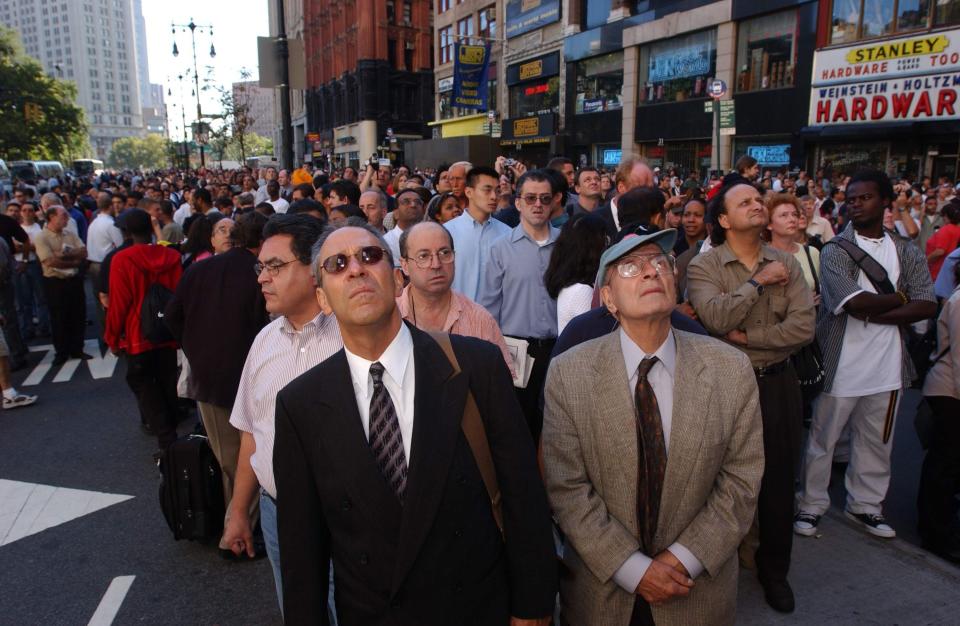 Spectators look up as the World Trade Center goes up in flames in New York City on September 11, 2001, after two planes crashed into the Twin Towers in a suspected terrorist attack.