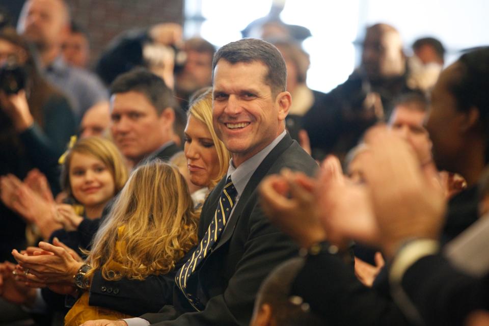 Jim Harbaugh smiles as he is introduced as the next Michigan football head coach, while sitting with his wife and family during a news conference in Ann Arbor on Dec. 30, 2014.