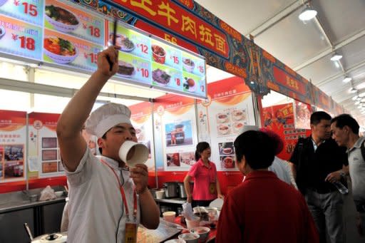 This file photo, taken in May, shows a vendor calling out to customers at a food court in Beijing. China's inflation rate eased to 3.0 percent in May, its lowest level since June 2010, according to latest official data, giving the government further room to loosen credit to boost flagging growth