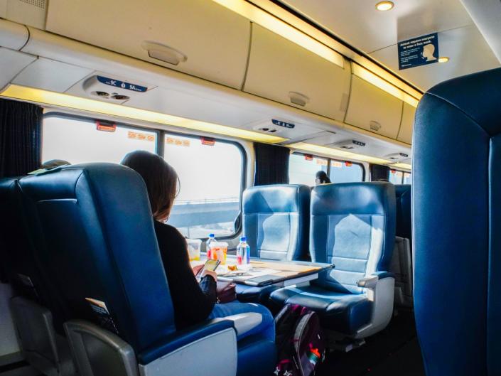 A person sits alone in an Amtrak Acela First class car