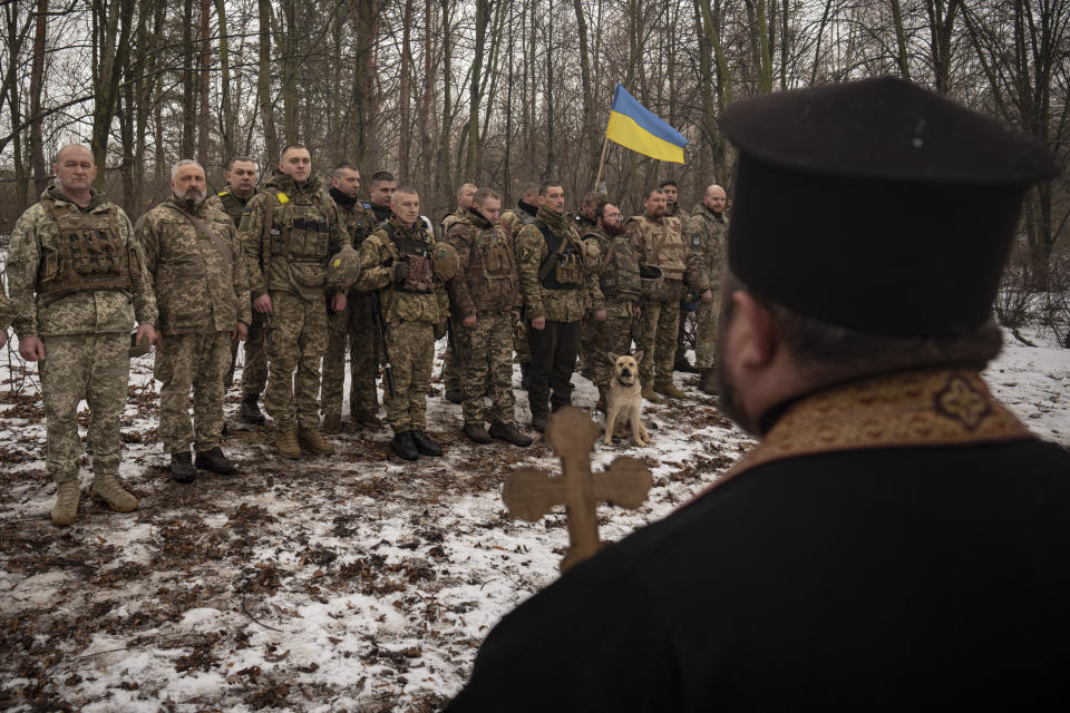 FILE - A priest blesses Ukrainian servicemen of the Prince Roman the Great 14th Separate Mechanized Brigade as they stand in formation during a flag ceremony where some of them were honored for their bravery and accomplishments in battle, in the Kharkiv area, Ukraine, Saturday, Feb. 25, 2023. Grueling artillery battles have stepped up in recent weeks in the vicinity of Kupiansk, a strategic town on the eastern edge of Kharkiv province by the banks of the Oskil River as Russian attacks intensifying in a push to capture the entire industrial heartland known as the Donbas, which includes the Donetsk and the Luhansk provinces. (AP Photo/Vadim Ghirda, File)