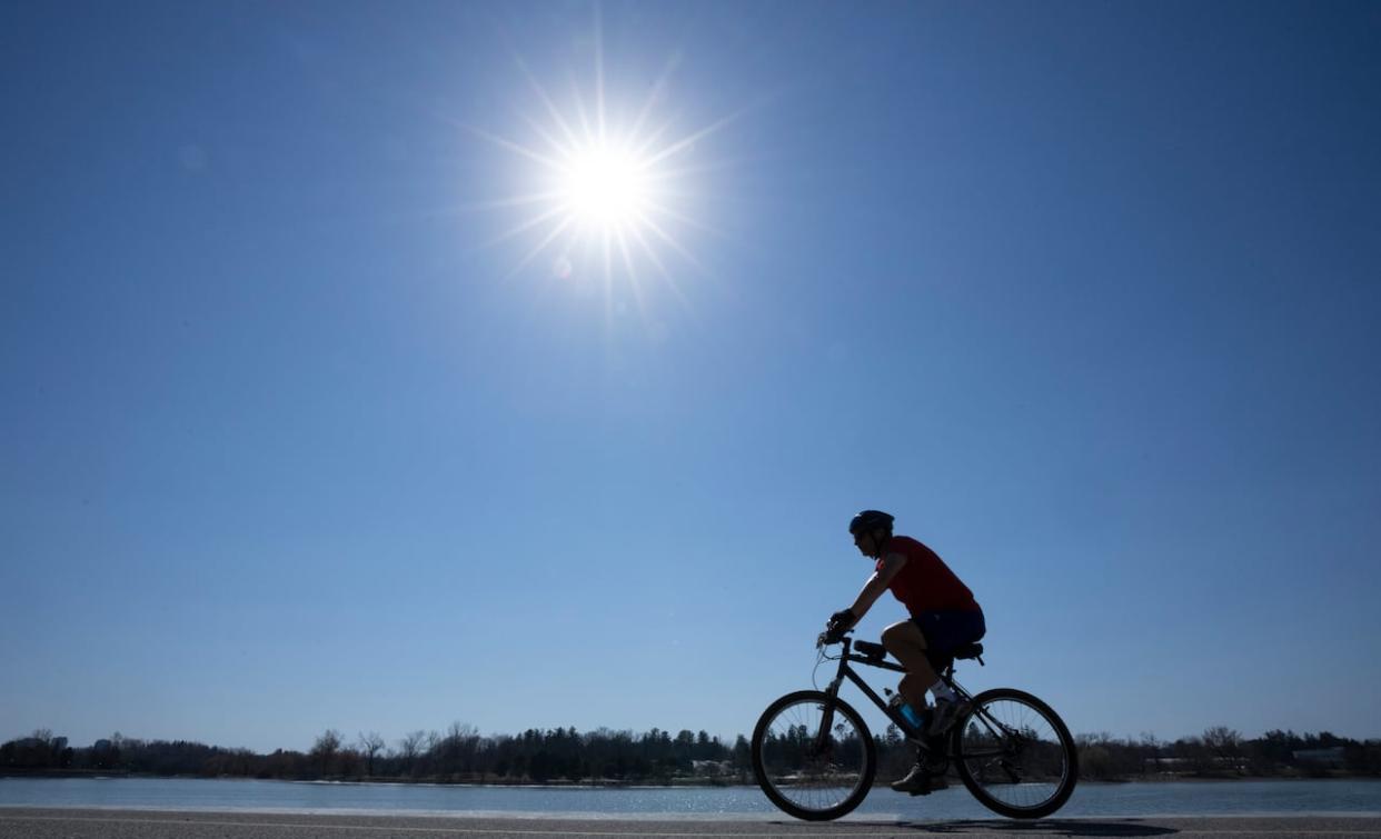 A cyclist makes their way along a bike path along Dow’s lake. Temperatures in the city are expected to stay high throughout the week.  (Adrian Wyld/The Canadian Press - image credit)