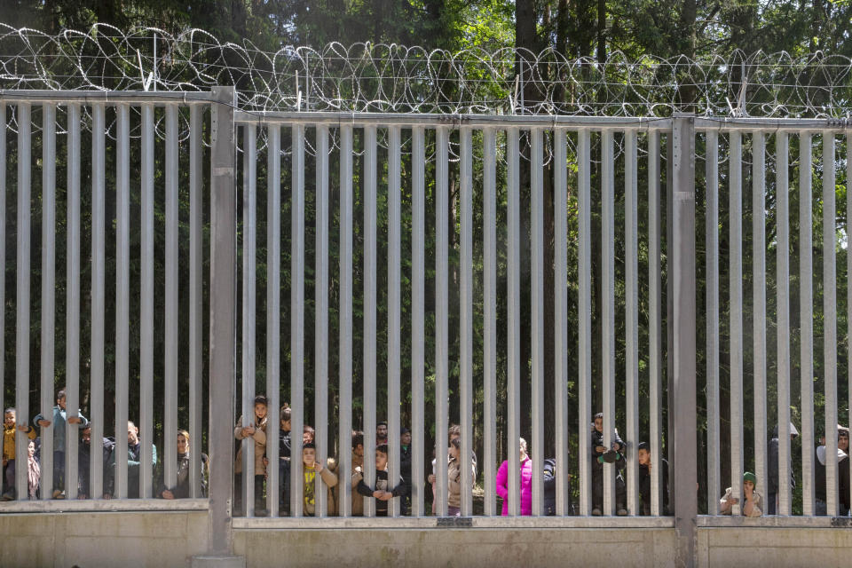 FILE - Members of a group of some 30 migrants seeking asylum look through the railings of a wall that Poland has built on its border with Belarus to stop massive migrant pressure, in Bialowieza, Poland, on May 28, 2023. Defense officials in NATO member Poland were presenting plans Monday, May 27, 2024, for fortifications and strengthening of its eastern border with Russia and Moscow ally Belarus. (AP Photo/Agnieszka Sadowska, File)