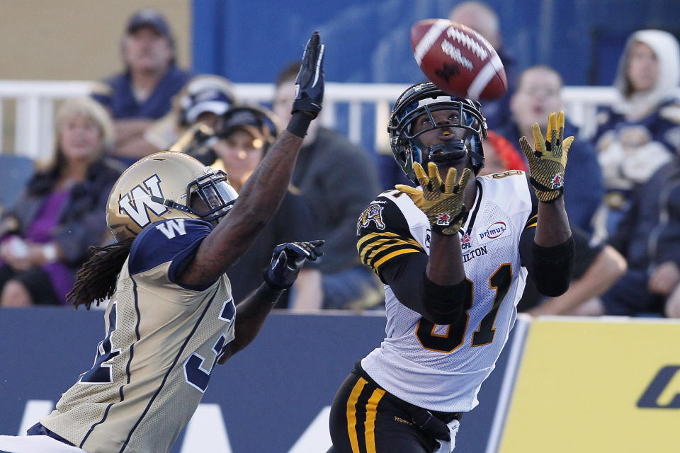 Hamilton Tiger-Cats' Aaron Kelly (81) hauls in a touchdown pass against Winnipeg Blue Bombers' Jeremy McGee (34) during the second half of their pre-season CFL game in Winnipeg Wednesday, June 20, 2012. THE CANADIAN PRESS/John Woods