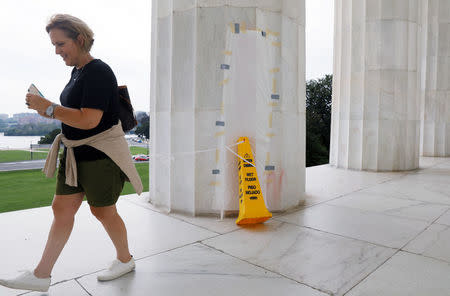 A tourist walks past a papered-over column where a vandal scrawled obscene graffiti in spray paint on the Lincoln Memorial in Washington, U.S. August 15, 2017. REUTERS/Jonathan Ernst