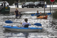 Kids kayak through the flooded streets near the corner of Mowbray Arch and Botetourt Street after the storms caused by Hurricane Dorian on Friday, Sept. 6, 2019, in Norfolk, Va. (Sarah Holm/The Virginian-Pilot via AP)