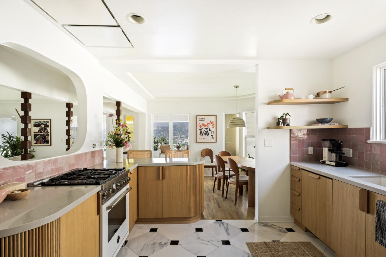  A kitchen with marble tiled flooring, wooden cabinetry, and a pink backsplash 