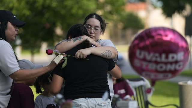 Visitors hug each other as they place flowers at a memorial in Uvalde, Texas, Wednesday, May 24, 2023.