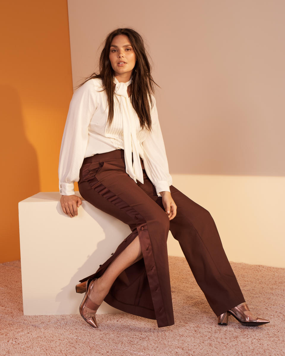 Candice Huffine wears a tie-neck blouse and dark brown split-leg trousers from the new Prabal Gurung x Lane Bryant collection. (Photo: Courtesy of Lane Bryant)