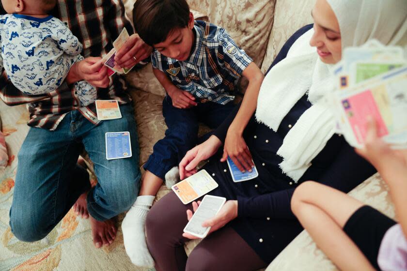 Tustin, CA - December 05: Sameer and Sara Ahmed with their children Imran, 7, and Aminah, 4, play a card game at their home on Tuesday, Dec. 5, 2023 in Tustin, CA. They are Muslim and do not celebrate Christmas. (Dania Maxwell / Los Angeles Times)