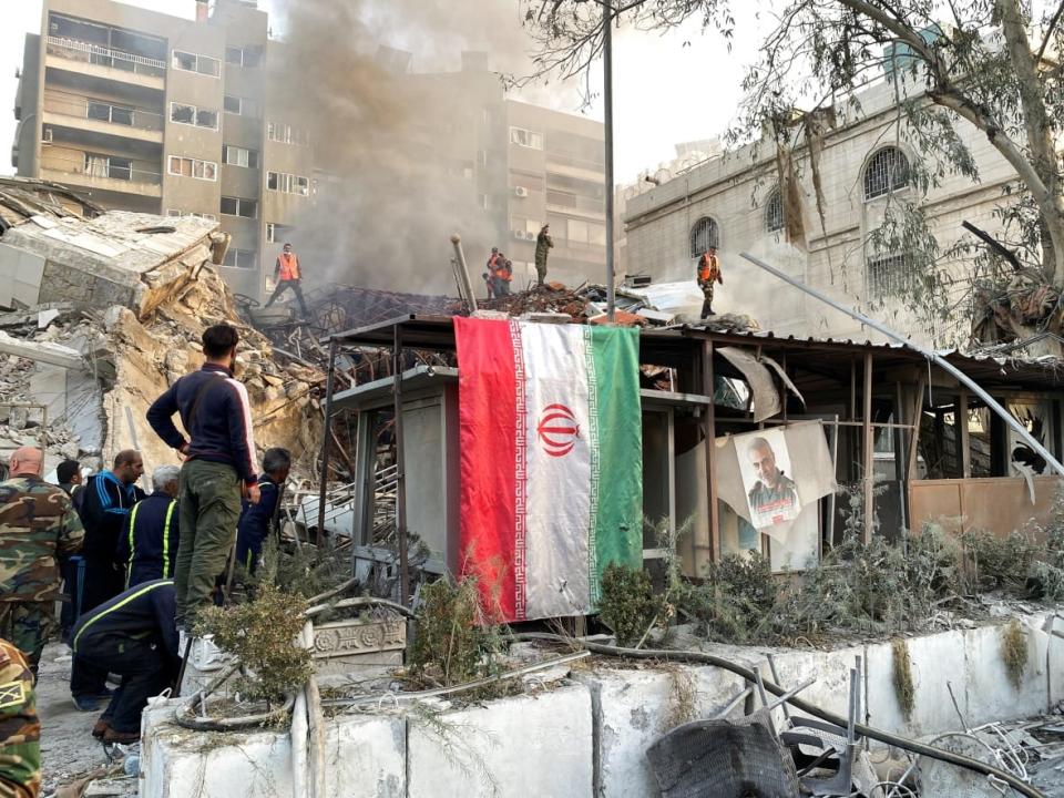 An Iranian flag hangs as smoke rises after what Iranian media said was an Israeli airstrike on a building close to the Iranian embassy in Damascus, Syria on Monday, April 1. (Firas Makdesi/Reuters - image credit)