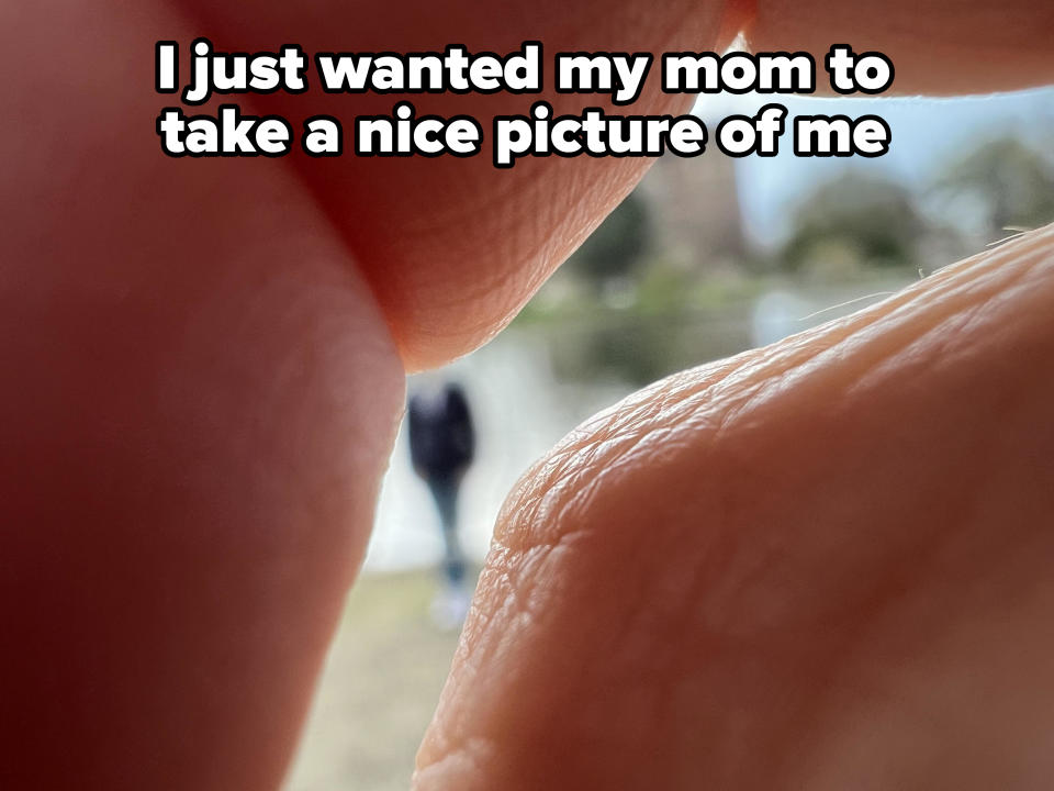 Person in distance framed between two fingers in a pinching gesture, focus on the fingers with blurry background