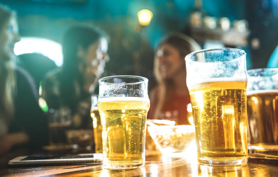 Happy girlfriends women group drinking beer at brewery bar restaurant - Friendship concept with young female friends enjoying time and having genuine fun at cool vintage pub - Focus on beer glasses