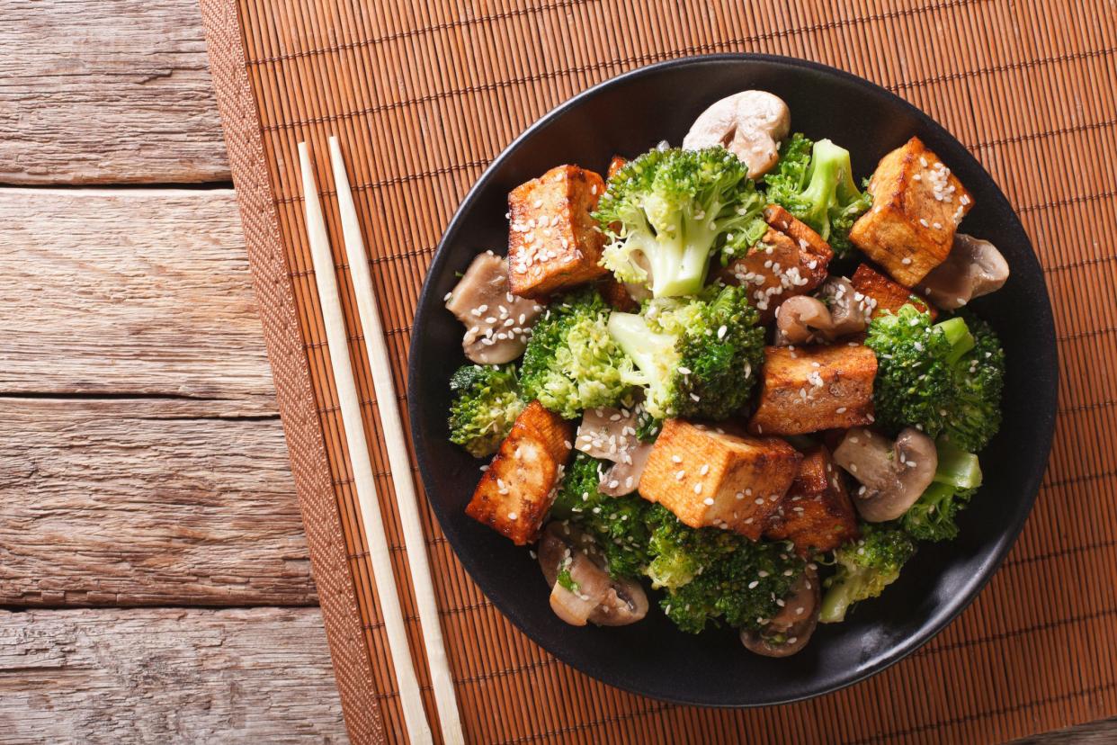 Savory sauteed mixed chinese vegetables with crispy fried tofu on a plate. Horizontal view from above