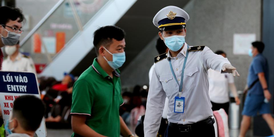 A staff member (R) from Vietnam's Centre of Disease Control assists passengers wearing face masks as they queue up for temperature checks at the departures terminal at Danang's international airport on July 27, 2020. (Photo by Hoang Khanh / AFP) (Photo by HOANG KHANH/AFP via Getty Images)