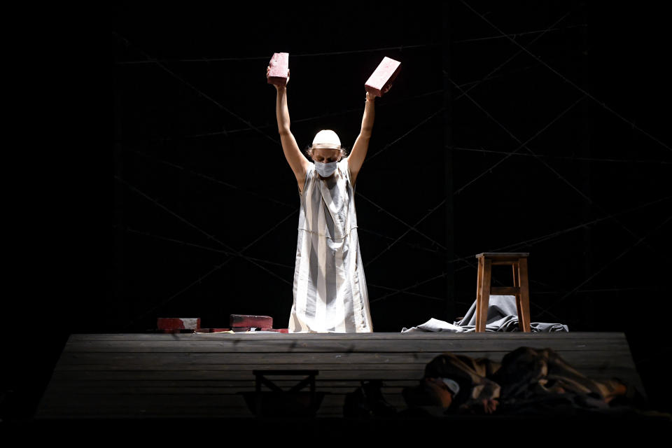 Alexandra Fasola of the Jewish State Theatre performs, wearing a face mask for protection against COVID-19 infection, during the premiere of the "The Beautiful Days of My Youth" play, based on the diary of Romanian Jewish Holocaust survivor Ana Novac, in Bucharest, Thursday, Oct. 15, 2020. Maia Morgenstern, head of the Jewish State Theater and a Romanian Jewish actress best known for playing Mary in Mel Gibson's controversial 2004 movie "The Passion of the Christ," described the play's staging in an interview with The Associated Press as an "all-feminine project." (AP Photo/Andreea Alexandru)