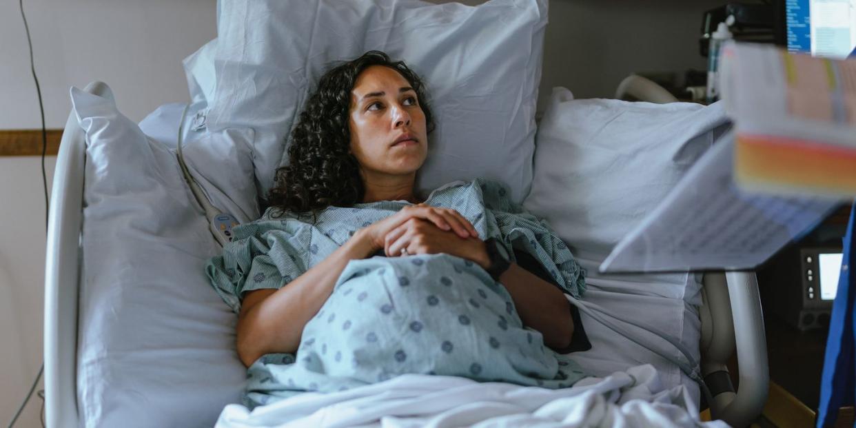 a pregnant woman lies in a hospital bed and speaks with her doctor while in labor