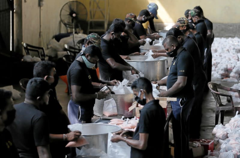 Sri Lankan civil Defence Force members load the essential food items packs into a truck to sell for low cost at a warehouse after the government imposed the nationwide curfew, in Colombo