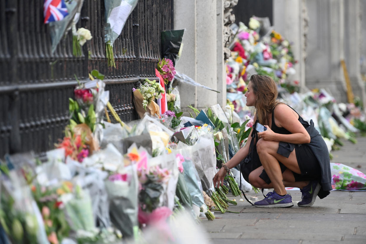 A woman places flowers outside the gates of Buckingham Palace.