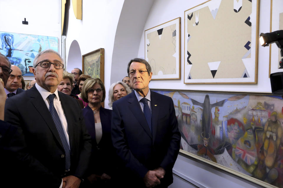 Cyprus' President Nicos Anastasiades, right, and Mustafa Akinci, the leader of the ethnically divided island's breakaway Turkish Cypriots, attend an exhibition of culturally significant paintings that were recently exchanged as part of an effort to boost confidence between the ethnically divided island nation's two communities, at the Ledra Palace Hotel inside a UN controlled buffer zone in divided capital Nicosia, Cyprus, Monday, Feb. 3, 2020. (AP Photo/Petros Karadjias)