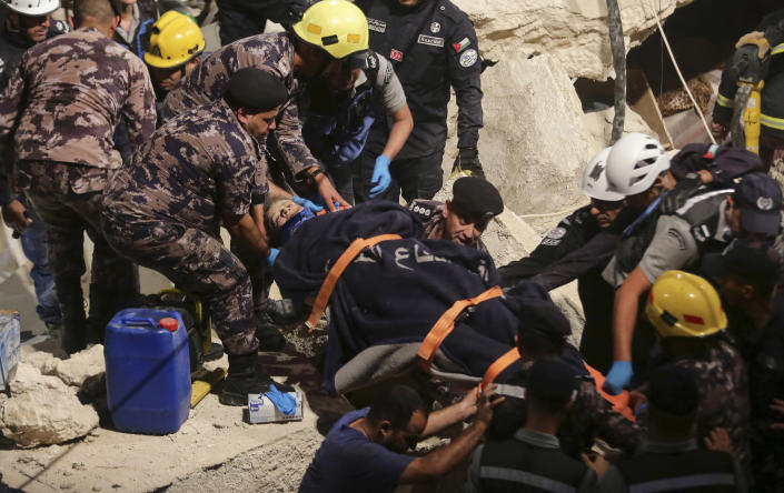 Civil Defense workers rescue a resident from a four-story building that collapsed killing several people and wounding others, in Amman, Jordan, on Tuesday Sept. 13, 2022. (AP Photo/Raad Adayleh)