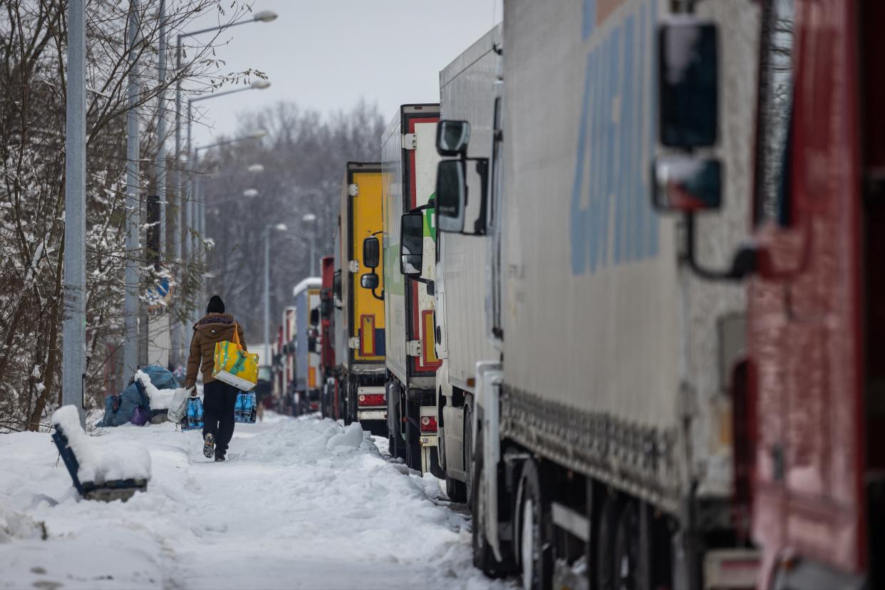 A Ukrainian truck driver walks past Ukrainian trucks as he carries bags full of groceries, on the parking lot near Korczowa Polish-Ukrainian border crossing (AFP via Getty Images)