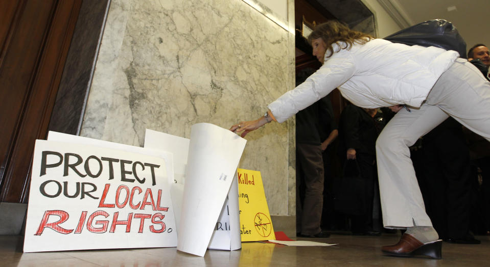 A woman picks up a sign as she leaves the the Pennsylvania state Supreme Courtroom in Pittsburgh where the court was hearing arguments from seven municipalities challenging portions of a new law that regulates natural gas exploration on Wednesday, Oct. 17, 2012. (AP Photo/Keith Srakocic)