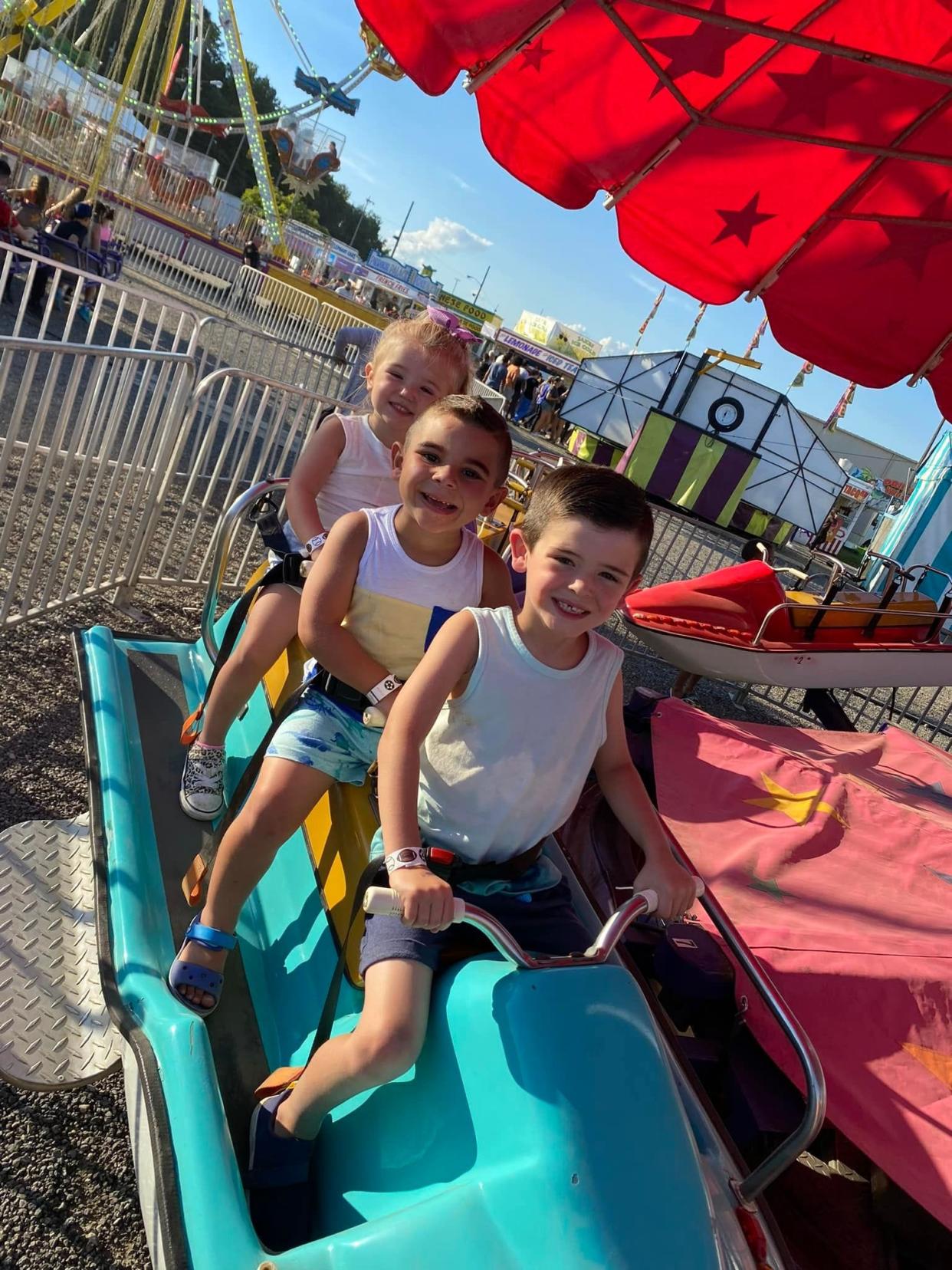 From front, Cruz Kramer, 5, Cohen Brown, 3, and Remi Kramer, 2, all from Rootstown, at the Summit County Fair. This photo was taken moments before the car they were on fell off of the ride and fell to the ground. They sustained minor injuries.