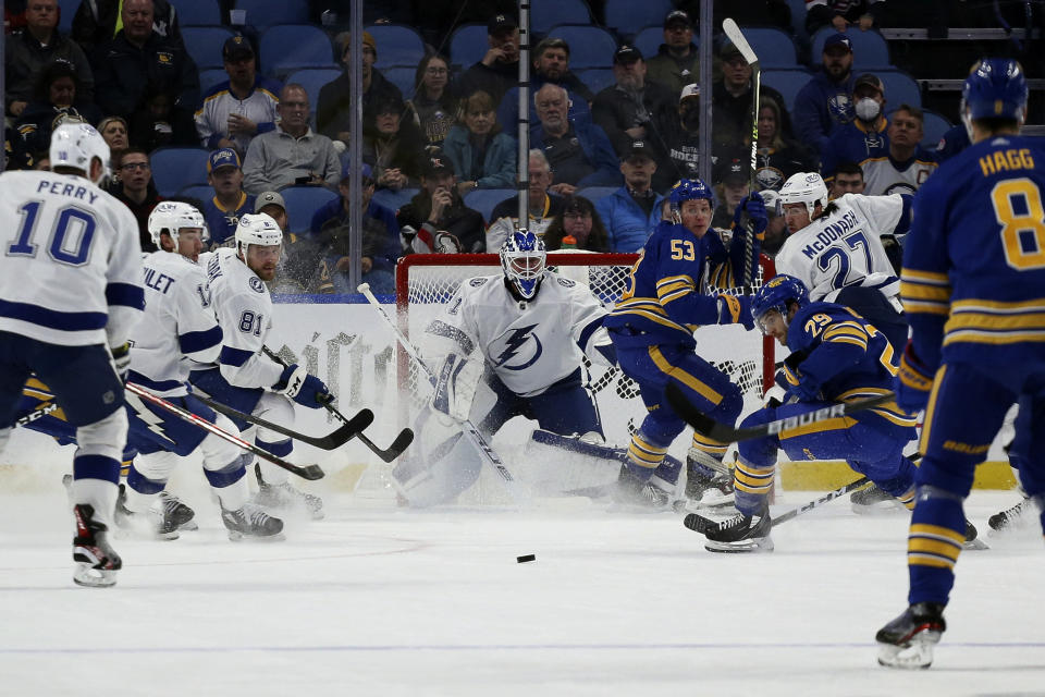 Players look at the puck after a shot by Buffalo Sabres left wing Jeff Skinner (53) was blocked by Tampa Bay Lightning goaltender Brian Elliott (1) during the first period of an NHL hockey game Monday, Oct. 25, 2021, in Buffalo, N.Y. (AP Photo/Joshua Bessex)