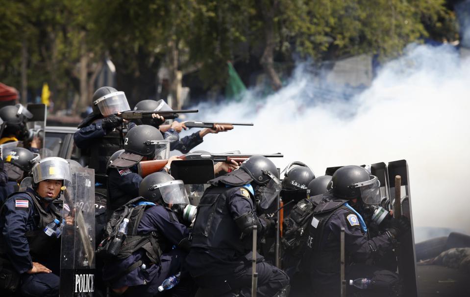 Thai policemen aim their weapons towards anti-government protesters during clashes near Government House in Bangkok